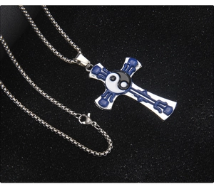 Détail macro du pendentif croix en acier avec émail bleu et symbole Yin Yang Bagua