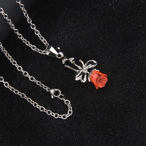 Collier minimaliste en acier argenté avec rose en résine rouge et pendentif noeud