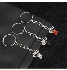 Macro detail of red, black, and clear resin rose keychains with silver bow accents