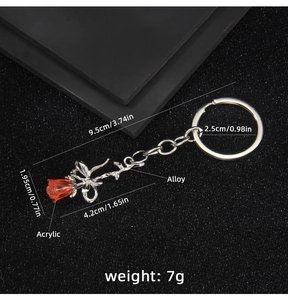 Detail view of red rose keychain with size and weight specs on a textured background