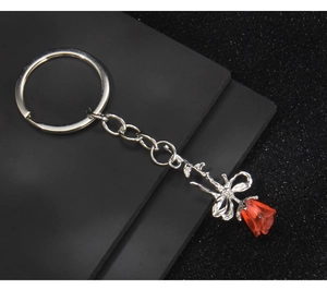 Detail of red rose keychain with silver metal stem and elegant leaf accents