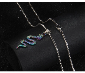 Macro detail of iridescent cobra snake pendant on black leather display with box chain