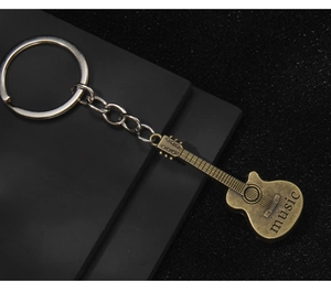 Detailed close-up of retro bronze guitar keychain with music engraving and metal chain