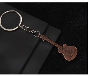 Detail of vintage bronze guitar keychain with music engraving on a textured black backdrop