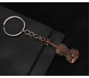 Detailed view of a vintage bronze violin keychain on a textured dark background