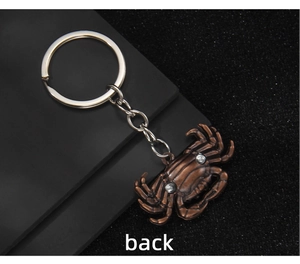 Detail view showing the back of the vintage bronze crab keychain with textured carvings