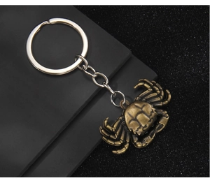 Macro shot of 3D bronze crab keychain with detailed vintage shell texture on grey matte stand
