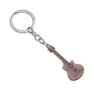 Vintage bronze guitar keychain with music engraving on a minimalist white background