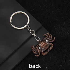 Back view of a vintage bronze crab keychain with textured metallic finish and silver ring