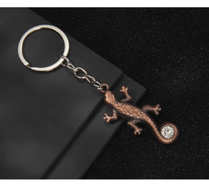 Détail d'un porte-clés lézard en métal bronze avec strass étincelant sur la queue