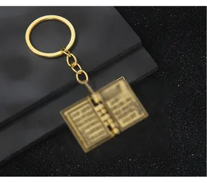 Gros plan du porte-clés pendentif livre en alliage doré avec détails gravés