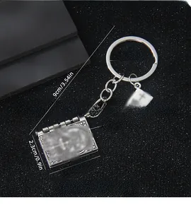 Détail macro du porte-clés mini livre avec motifs vintage et pendentif croix