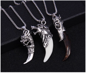 Detailed view of three vintage ethnic faux wolf tooth pendants with engraved metal animal heads