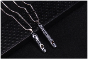 Détail de deux pendentifs sifflets en argent vintage sur fond texturé noir