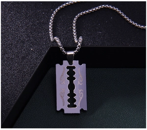 Vue macro d'un pendentif lame de rasoir en acier inoxydable aux motifs gravés
