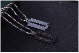 Vue macro de pendentifs lame argent et noir sur chaînes box sur une surface texturée