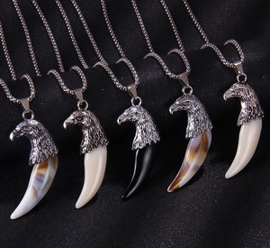 Détail de cinq colliers tête d'aigle rétro avec pendentifs dents en résine sur chaînes