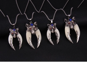 Detailed view of four punk style wolf head necklaces with ivory tusks and blue gemstones