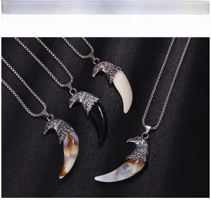 Détail de pendentifs dent de loup avec têtes d'aigle en plusieurs couleurs et textures