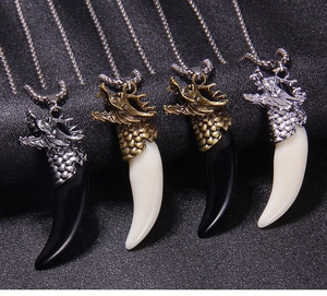 Close-up of four dragon head pendants with faux wolf fangs in various vintage metal finishes
