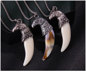 Vue détaillée de pendentifs tête d'aigle et crocs de loup sur un support noir texturé