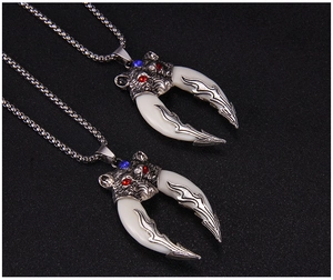 Detail of wolf head pendant with red and blue gemstones on a long stainless steel chain