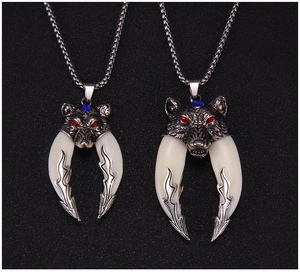 Detailed macro view of two vintage wolf head pendants with curved tusks on box chains