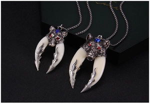 Detailed view of dual wolf tooth pendant necklace with red rhinestones and blue gems
