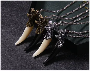 Detail of dragon head wolf tooth pendants in bronze and silver with intricate carving