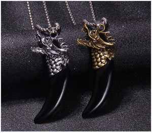 Detailed close-up of retro dragon head pendants with faux wolf tooth in silver and bronze finish