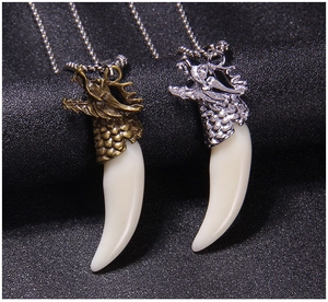 Close-up of retro dragon head pendants with faux wolf fangs in gold and silver finish