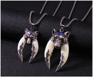 Detail of wolf head pendants with red and blue zircon eyes on a steel chain necklace