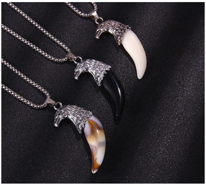 Vue détaillée de trois pendentifs tête d'aigle avec crocs de loup en noir, blanc et marron