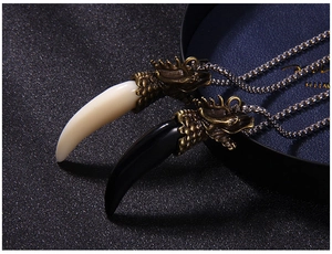 Macro shot of bronze dragon head and faux fang pendants on silver bead chains