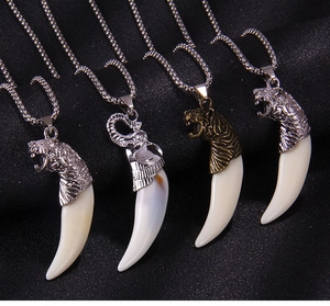 Vue détaillée des pendentifs tête de tigre et dent de loup en argent et bronze antique