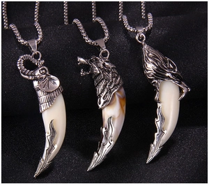 Close-up of retro animal head pendants with curved ivory-shaped tusks on black fabric