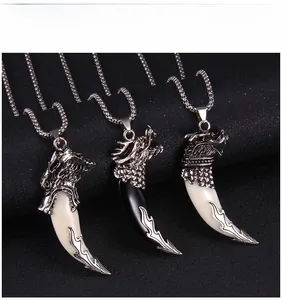 Close-up of vintage dragon head pendant with wolf tooth resin element and steel chain