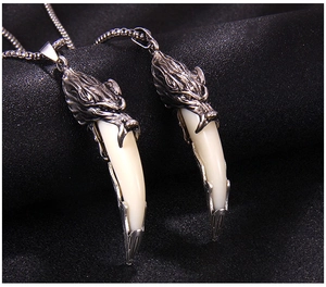Macro detail of retro wolf head pendants with faux ivory fangs on black textured fabric
