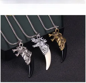 Détail de pendentifs vintage en forme de dragon et dent de loup, argent et bronze