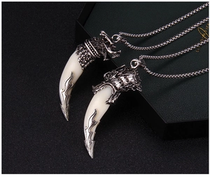 Detailed view of vintage silver wolf head pendant with ivory-white tooth and metal chain