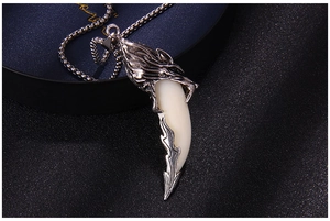 Macro view of silver wolf head pendant with white faux tooth and intricate flame engraving