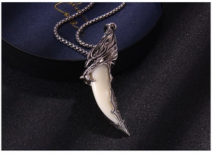 Macro shot of silver metal wolf fang pendant with detailed beast claw cap on black base