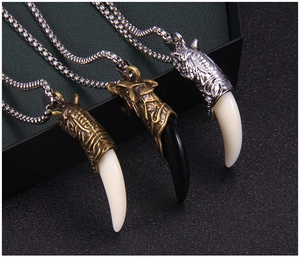 Détail de trois pendentifs vintage en acier inoxydable avec dents de loup pour hommes