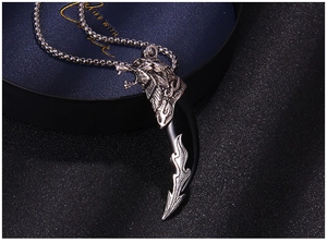 Detailed view of silver wolf head relief and black fang pendant on a square link chain