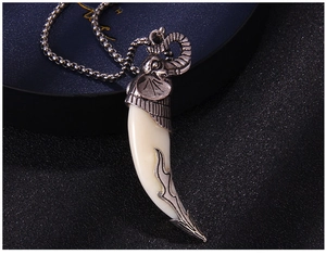Close-up of retro silver elephant head pendant with crescent tusk and metal ball chain