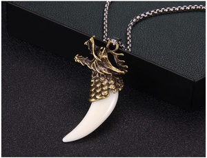 Détail du pendentif tête de dragon vintage avec dent de loup factice sur une chaîne à billes