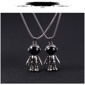 Détail de pendentifs astronaute en argent avec texture de combinaison et visière noire