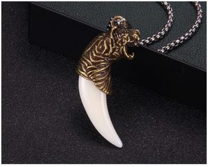 Détail macro d'un pendentif tigre vintage avec dent de loup factice sur chaîne à billes