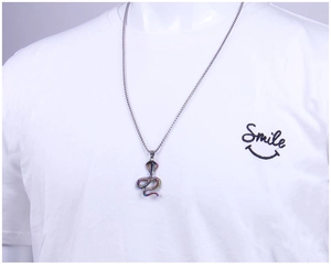 Detail of colorful cobra pendant necklace with rainbow finish on white t-shirt