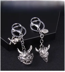 Macro detail of gothic punk silver keychains featuring demon mask and skull designs